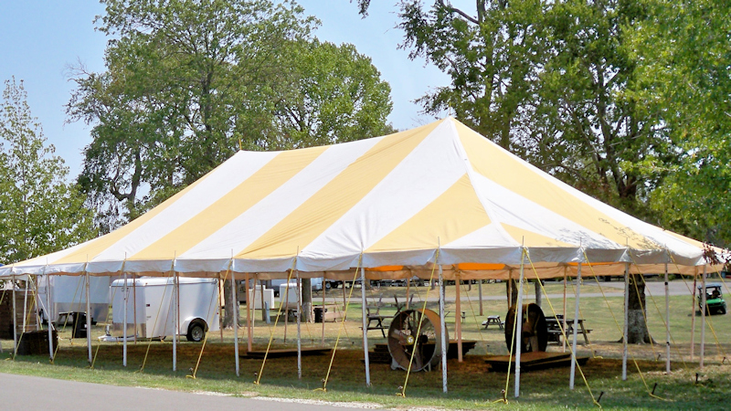Yellow striped tent canopy on lawn and with fans.